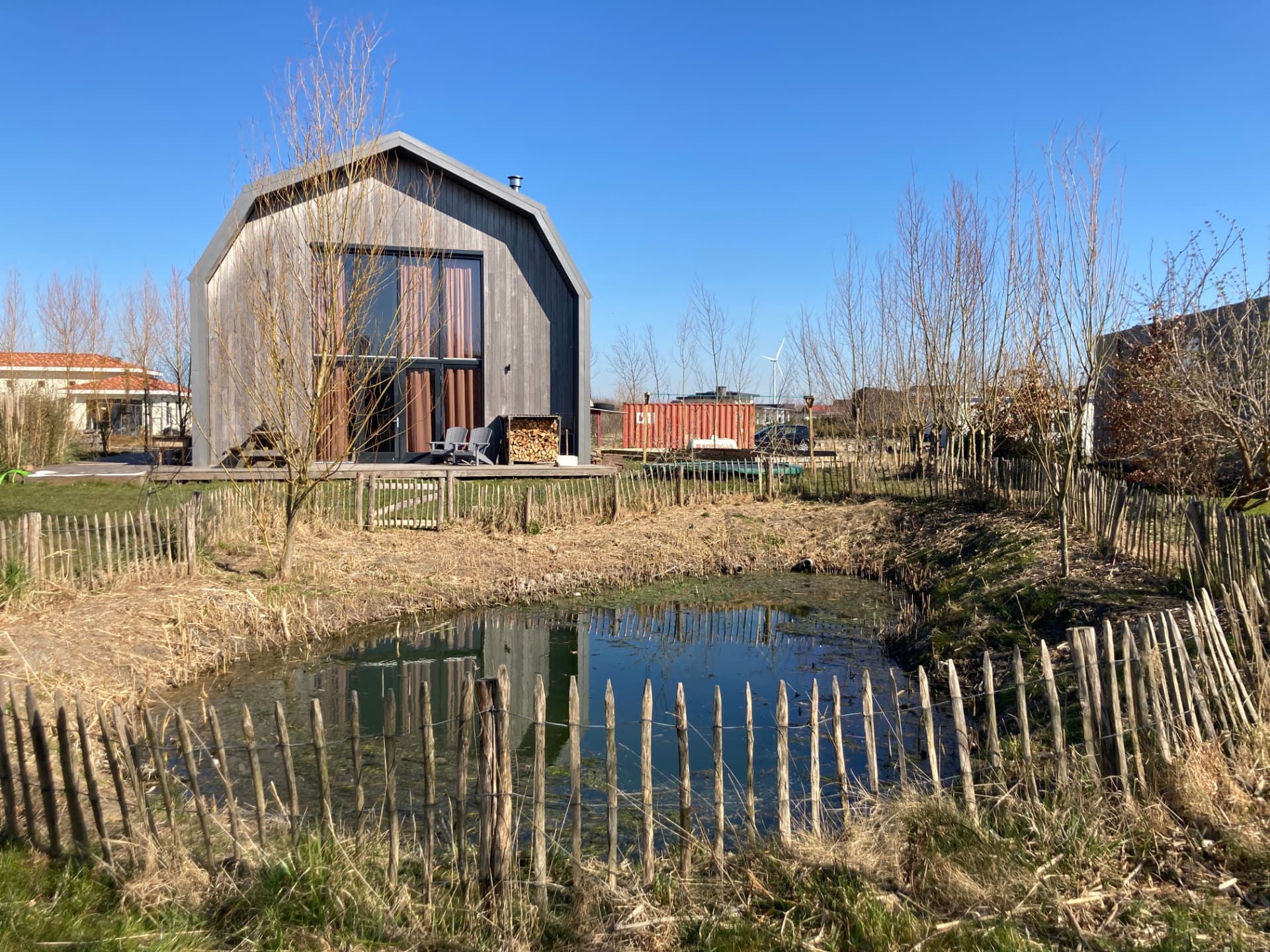 Bestaande situatie op de kavel: houten woning met vijver en jonge aanplant
