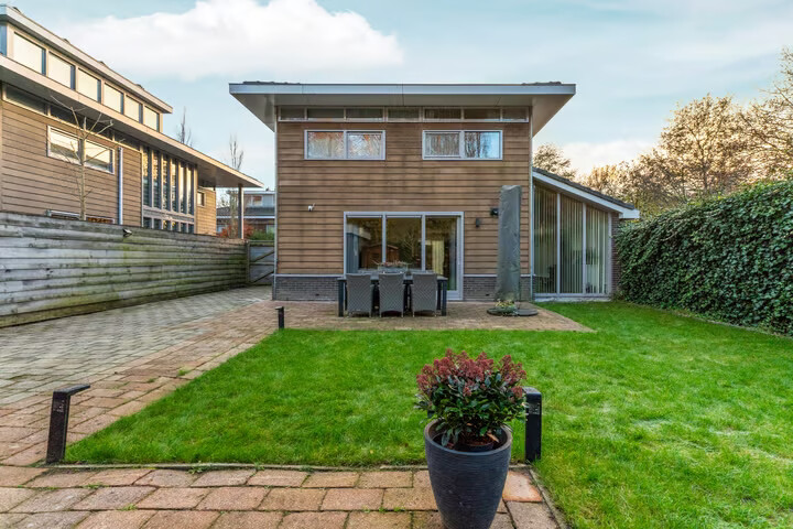 Achterzijde van de woning met terras en gazon, de plek van de toekomstige vijver