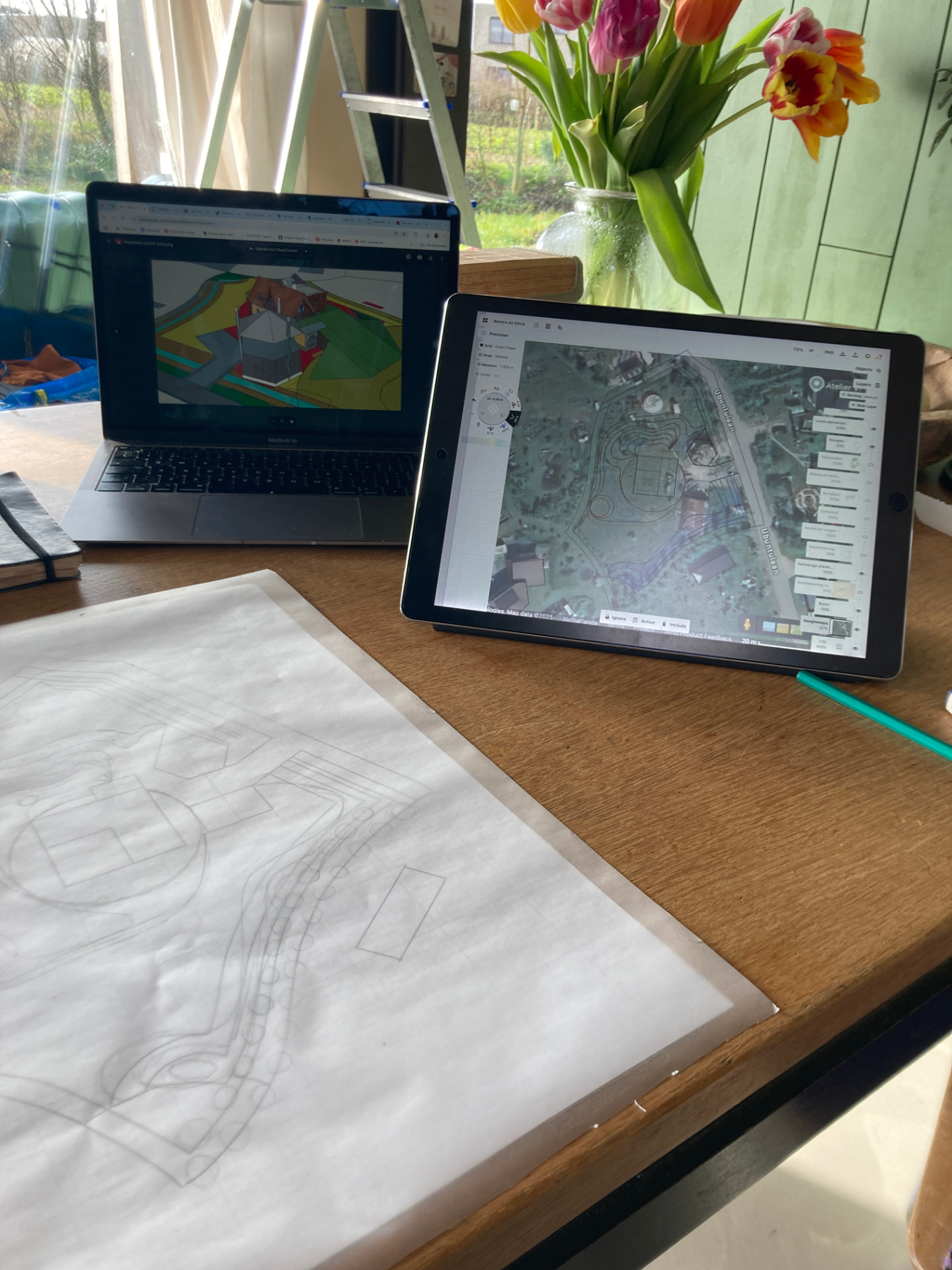 Ontwerpwerkplek met laptop, tablet en potloodschets van een tuinontwerp