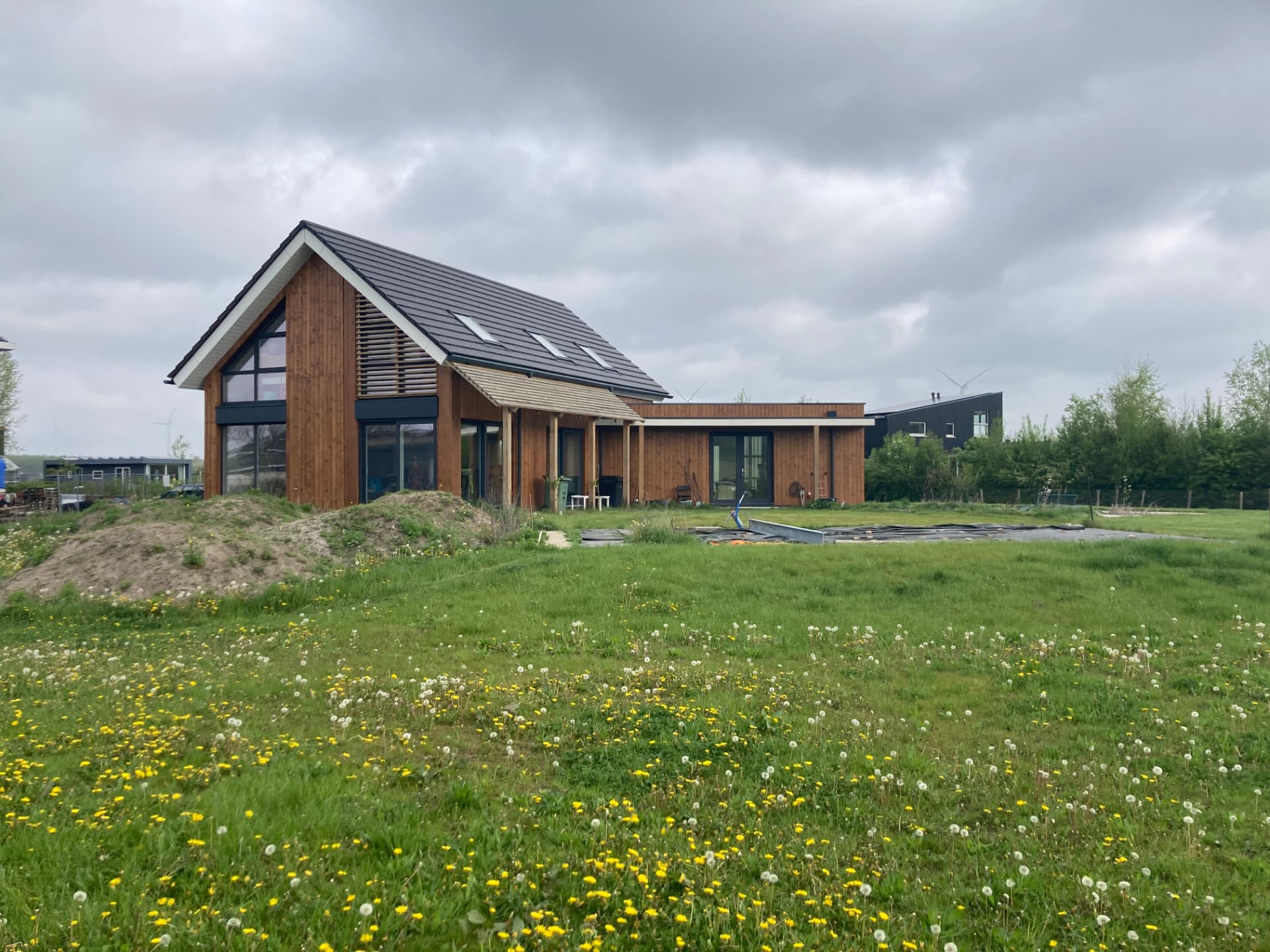 De woning met houten gevel en het open veld met bloeiend gras